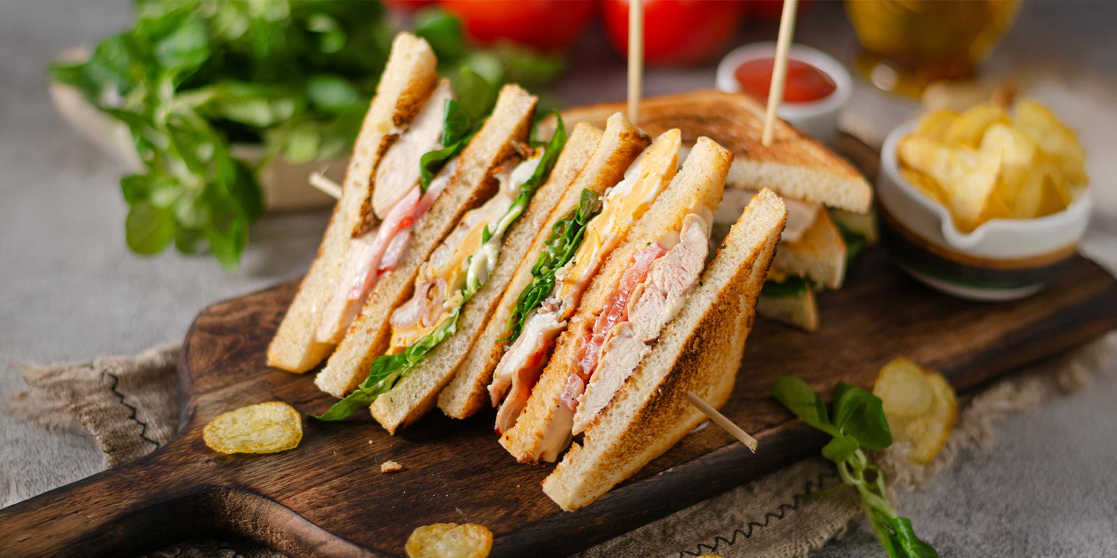 A sandwich with chips lying on a wooden cutting board